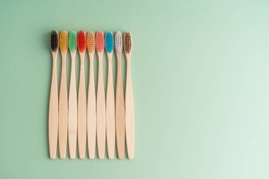 Açık yeşil arka planda bambu ağacından yapılmış çevre dostu antibakteriyel diş fırçaları. Çevresel bakım eğilimleri.