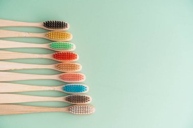 Açık yeşil arka planda bambu ağacından yapılmış çevre dostu antibakteriyel diş fırçaları. Çevresel bakım eğilimleri.