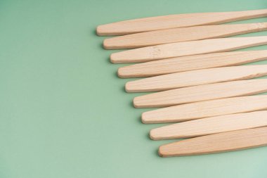 Açık yeşil arka planda bambu ağacından yapılmış çevre dostu antibakteriyel diş fırçaları. Çevresel bakım eğilimleri.