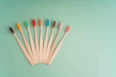 Açık yeşil arka planda bambu ağacından yapılmış çevre dostu antibakteriyel diş fırçaları. Çevresel bakım eğilimleri.