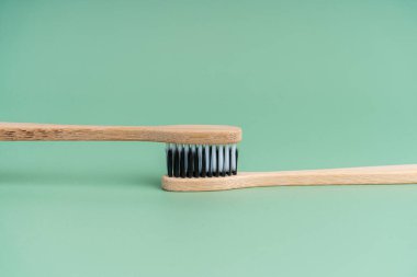 Açık yeşil arka planda beyaz ve siyah tüylü iki çevre dostu antibakteriyel bambu ahşap diş fırçası. Çevreyle ilgilenmek moda. Hoşgörü. Boşluğu kopyala.