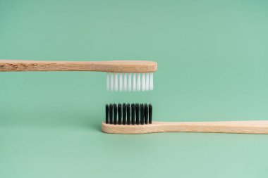 Açık yeşil arka planda beyaz ve siyah tüylü iki çevre dostu antibakteriyel bambu ahşap diş fırçası. Çevreyle ilgilenmek moda. Hoşgörü. Boşluğu kopyala.