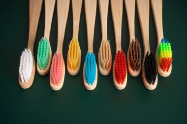 Koyu yeşil arka planda bambu ağacından yapılmış çevre dostu antibakteriyel diş fırçaları. Çevresel eğilimler.