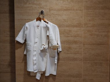 Banyo duvarında beyaz cübbe var. Banyo yaptıktan sonra bornoz.