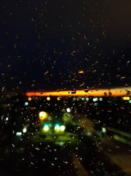 玻璃上的雨滴 日落时还活着带着明亮橙色条纹的夜空 — 图库照片