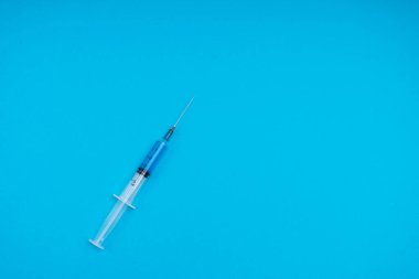 Mavi zemin üzerinde aşı olan tıbbi şırınga..