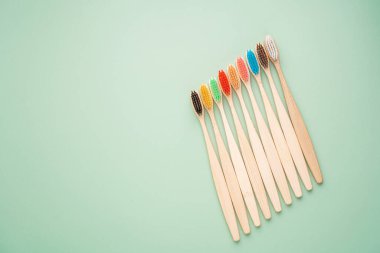 Açık yeşil arka planda bambu ağacından yapılmış çevre dostu antibakteriyel diş fırçaları. Çevresel bakım eğilimleri.