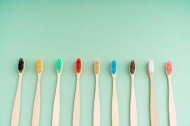 Açık yeşil arka planda bambu ağacından yapılmış çevre dostu antibakteriyel diş fırçaları. Çevresel bakım eğilimleri.