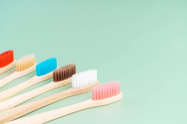 Açık yeşil arka planda bambu ağacından yapılmış çevre dostu antibakteriyel diş fırçaları. Çevresel bakım eğilimleri.
