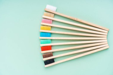 Açık yeşil arka planda bambu ağacından yapılmış çevre dostu antibakteriyel diş fırçaları. Çevresel bakım eğilimleri.
