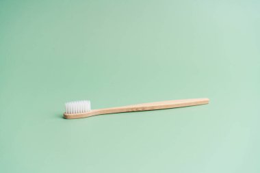 Çevre dostu bambu ahşap antibakteriyel diş fırçası açık yeşil arka planda.