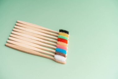 Açık yeşil arka planda bambu ağacından yapılmış çevre dostu antibakteriyel diş fırçaları. Çevresel bakım eğilimleri.