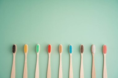 Açık yeşil arka planda bambu ağacından yapılmış çevre dostu antibakteriyel diş fırçaları. Çevresel bakım eğilimleri.