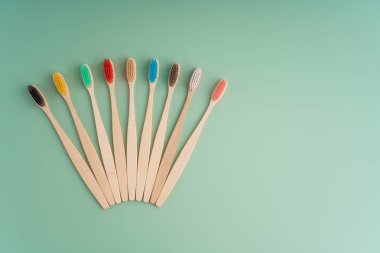 Açık yeşil arka planda bambu ağacından yapılmış çevre dostu antibakteriyel diş fırçaları. Çevresel bakım eğilimleri.
