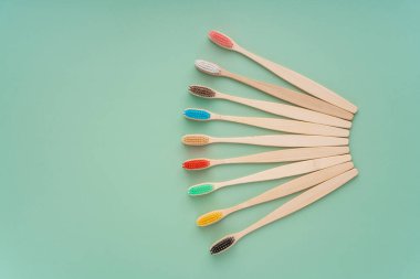 Açık yeşil arka planda bambu ağacından yapılmış çevre dostu antibakteriyel diş fırçaları. Çevresel bakım eğilimleri.