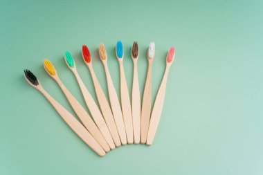 Açık yeşil arka planda bambu ağacından yapılmış çevre dostu antibakteriyel diş fırçaları. Çevresel bakım eğilimleri.