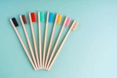 Açık yeşil arka planda bambu ağacından yapılmış çevre dostu antibakteriyel diş fırçaları. Çevresel bakım eğilimleri.