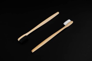 Siyah arka planda beyaz ve siyah tüyleri olan iki çevre dostu antibakteriyel bambu ahşap diş fırçası. Çevreyle ilgilenmek moda. Hoşgörü. Boşluğu kopyala.