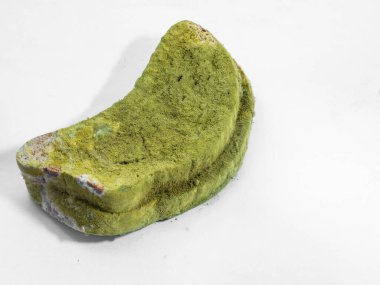 Beyaz arka planda yeşil küfle kaplı bir parça ekmek izole edilmiş..