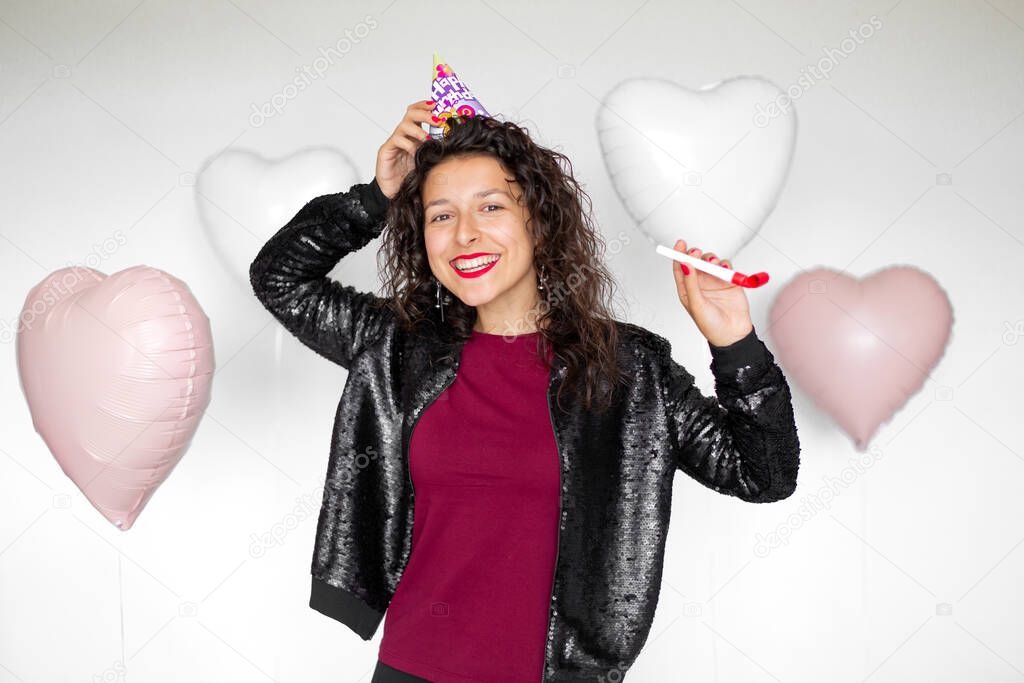 Sexy brunette girl posing with heart-shaped balloons on a white background.