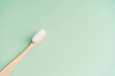 Çevre dostu diş sağlığı antibakteriyel bambu ahşap diş fırçası yeşil arka planda.