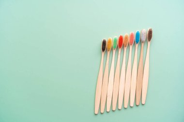 Açık yeşil arka planda bambu ağacından yapılmış çevre dostu antibakteriyel diş fırçaları. Çevresel bakım eğilimleri.