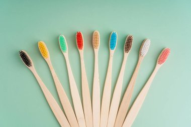 Açık yeşil arka planda bambu ağacından yapılmış çevre dostu antibakteriyel diş fırçaları. Çevresel bakım eğilimleri.