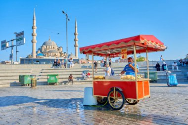 İstanbul 'da yaz caddesinde el arabasından ızgara mısır satan bir adam. Türk sokak yemekleri işi. Türkiye, İstanbul - 21.07.2020