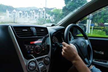 Arabanın içi. Adam yağmurlu havada araba sürüyor. Cameron Highlands, Malezya - 06.17.2020