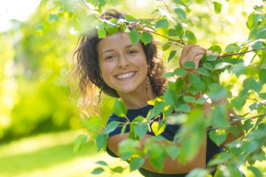 Genç ve güzel esmerin portresi Yeşil yaz parkında yürümenin keyfini çıkar.