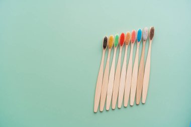 Açık yeşil arka planda bambu ağacından yapılmış çevre dostu antibakteriyel diş fırçaları. Çevresel bakım eğilimleri.