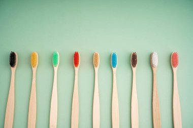 Açık yeşil arka planda bambu ağacından yapılmış çevre dostu antibakteriyel diş fırçaları. Çevresel bakım eğilimleri.