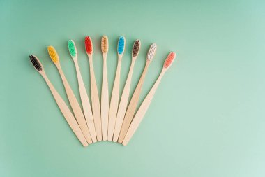 Açık yeşil arka planda bambu ağacından yapılmış çevre dostu antibakteriyel diş fırçaları. Çevresel bakım eğilimleri.