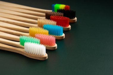 Koyu yeşil arka planda bambu ağacından yapılmış çevre dostu antibakteriyel diş fırçaları. Çevresel eğilimler.