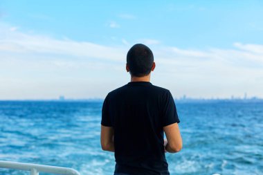 Adam feribotun üzerinden uçan martılara ekmek atıyor..