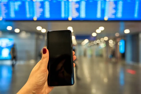 Smartphone Handen Mot Bakgrund Informationstavlan Flygplatsen — Stockfoto