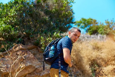 Hafta sonu yürüyüşü. Sırt çantalı bir adam kayalıklarda yürüyor. Aktif dinlenme ve doğanın keyfi.