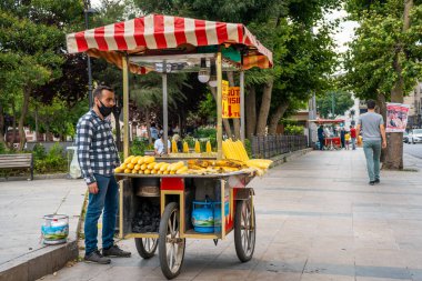 İstanbul 'da yaz caddesinde el arabasından ızgara mısır satan bir adam. Türk sokak yemekleri işi. İstanbul, Türkiye - 28.07.2017