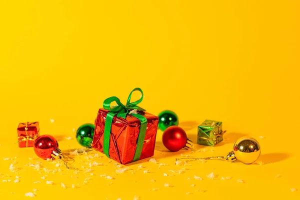Geschenkdoos Met Een Kerstcadeau Een Gele Achtergrond Tussen Nieuwjaarsdecoraties — Stockfoto
