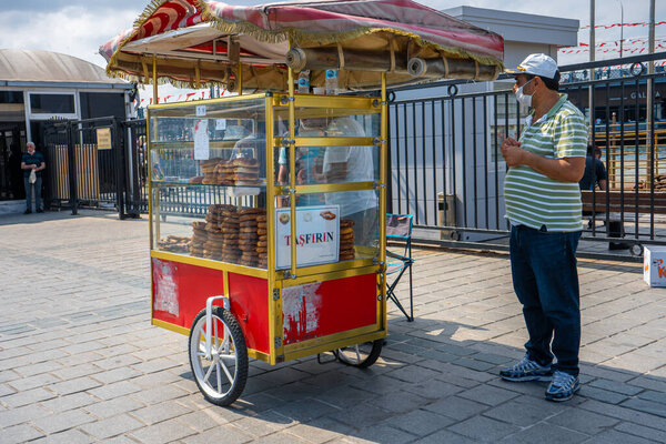 Man sale traditional Turkish bagel simit from cart on the summer Istanbul street. Istanbul, Turkey - 28.07.2017