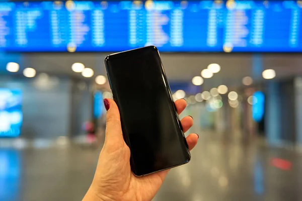 Smartphone Handen Mot Bakgrund Informationstavlan Flygplatsen — Stockfoto