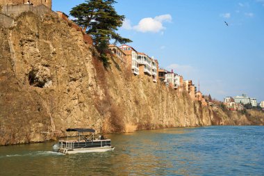 Tiflis 'in eski mimarisi. Nehir kıyısındaki bir uçurumun kenarında yoğun bir yerleşim yeri inşaatı. Tiflis, Gürcistan - 03.17.2021