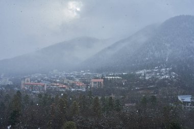 Kış dağı manzarası. Dağlar arasında küçük bir kasaba. Şehrin üzerinde bir bulut asılı..