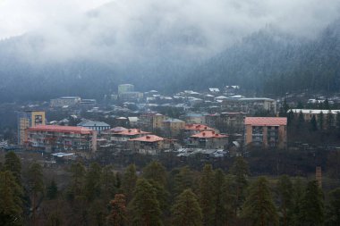 Kış dağı manzarası. Dağlar arasında küçük bir kasaba. Şehrin üzerinde bir bulut asılı..