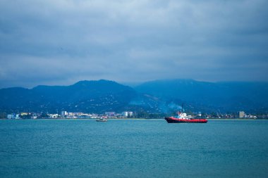 Batumi açıklarında Karadeniz 'de bir gemi. Dağların arka planına karşı Karadeniz suları.