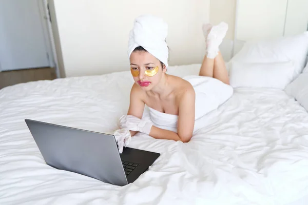 수건으로 소녀는 노트북으로 작업을 피부에 바르는 화장품 사용하여 물기를 집에서 — 스톡 사진