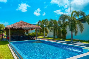 Bahçesinde yüzme havuzu olan rahat bir tropikal tatil köyü. Parlak güneşli bir gün.