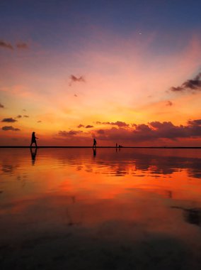 Okyanus kıyısında bulutlu, yakıcı gün batımı.