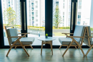 Parlak bir odanın minimalist modern iç mekanı. Masa ve sandalyeler büyük pencerenin yanında..