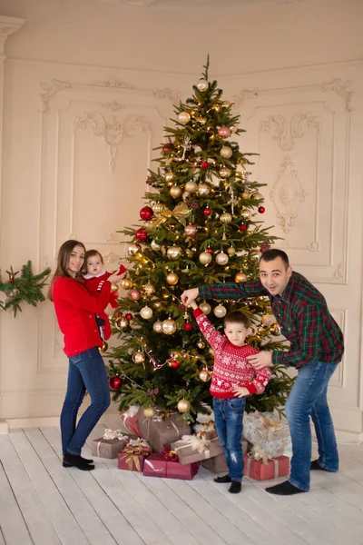 Happy family decorate the Christmas tree indoors together. Loving family. Merry Christmas and Happy Holidays.